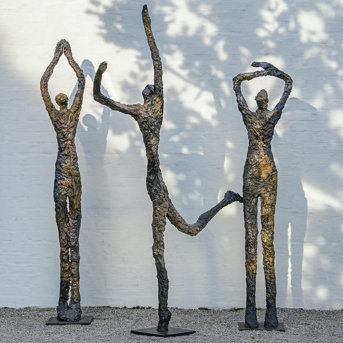 Bronzeskulpturen vor weißer Mauer
